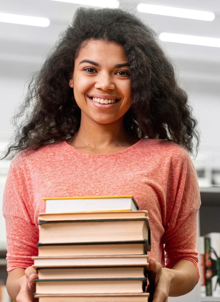 Girl smiling and holding a stack of books